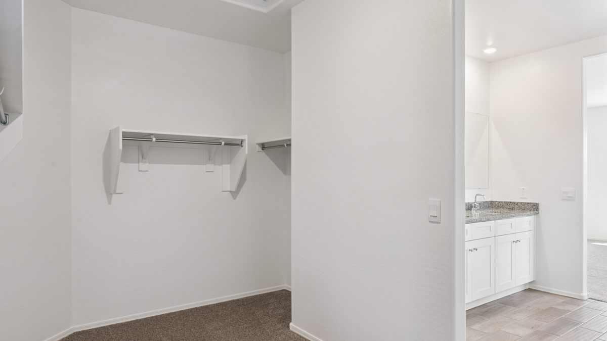 Modern primary bathroom with double vanity, granite countertops with a walk-in shower and a walk-in closet.