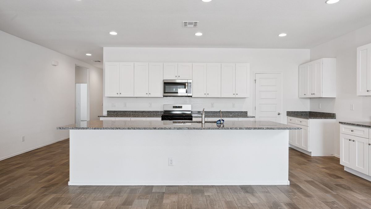 Bright and spacious kitchen with granite countertops, stainless steel appliances, and an island with bar seating.
