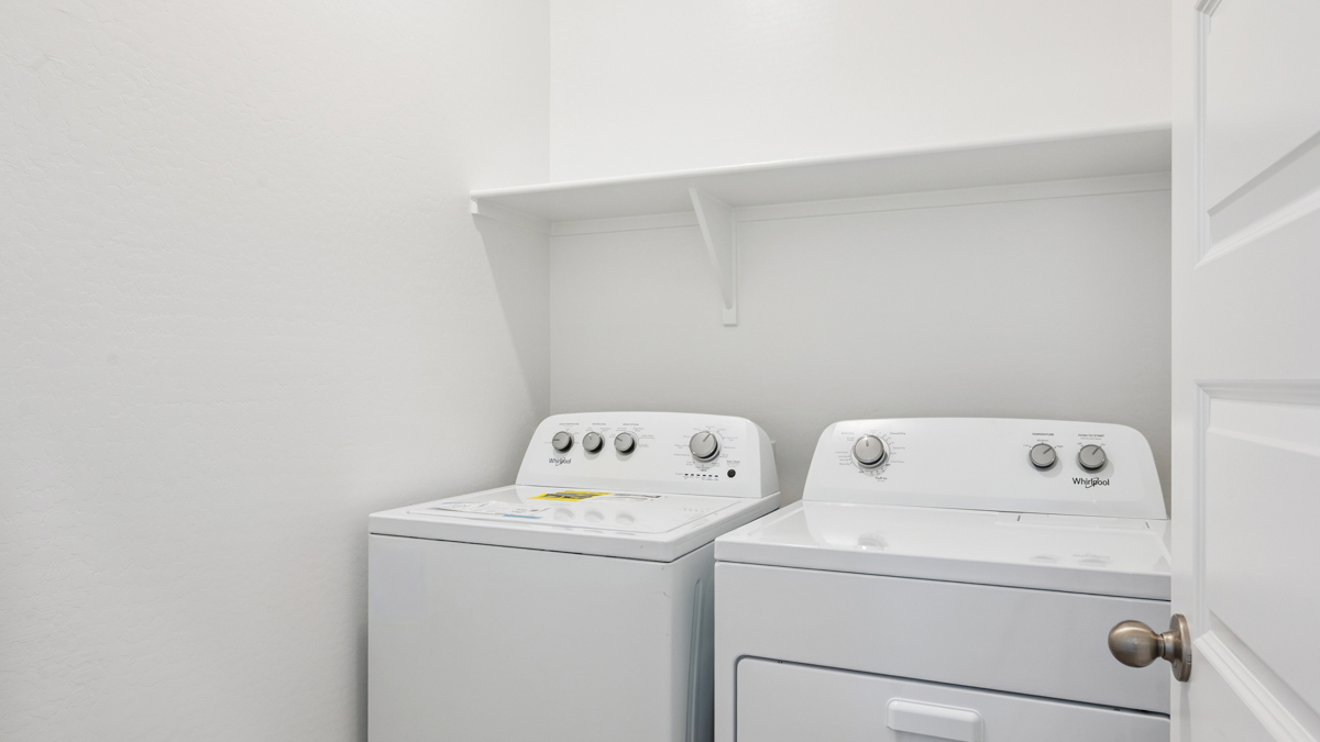 Spacious laundry room with washer and dryer connections and shelving for storage.
