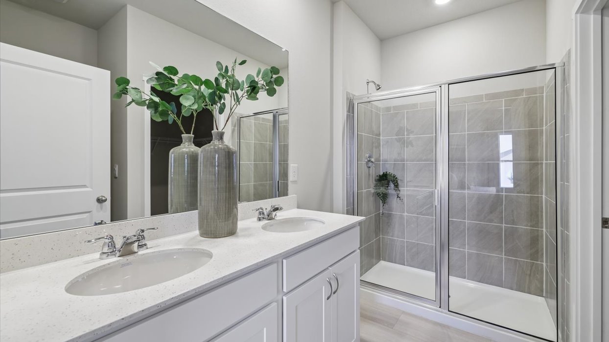roland primary bathroom with tile shower and dual sinks