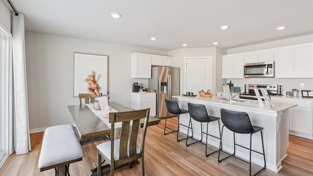 dining area with wood dining table next to modern white kitchen