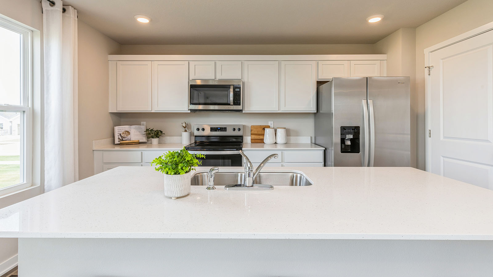 Kitchen with stainless steel appliances, quartz countertops, and white cabinetry