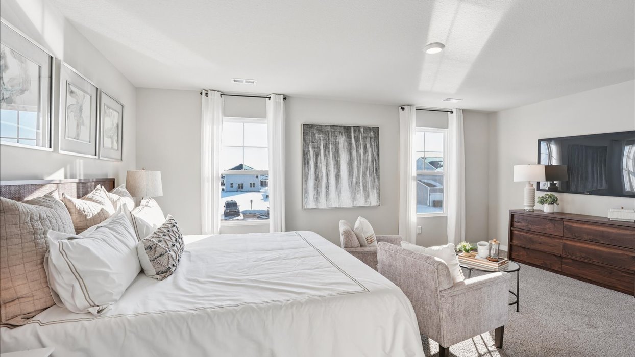 primary bedroom with white bed and wood dresser