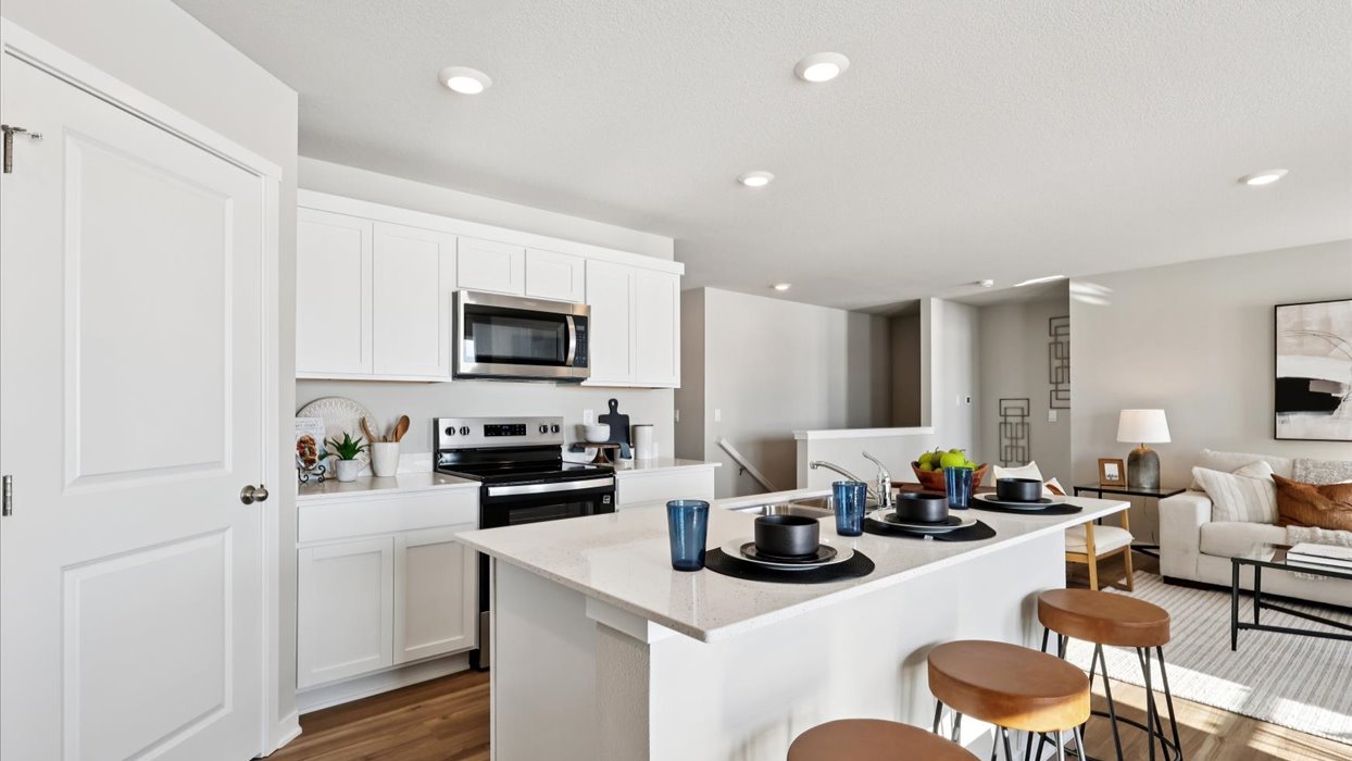 Kitchen with stainless steel appliances, quartz countertops, and white cabinetry