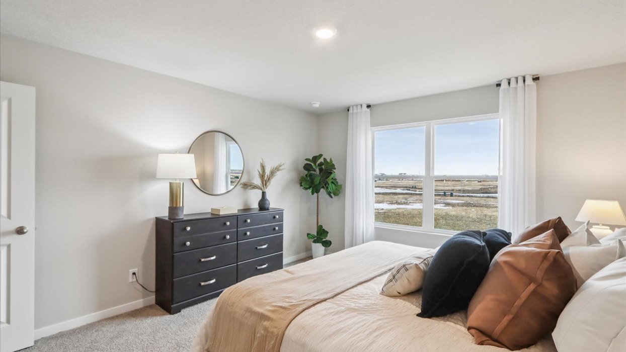 primary bedroom with large window and bed with dresser