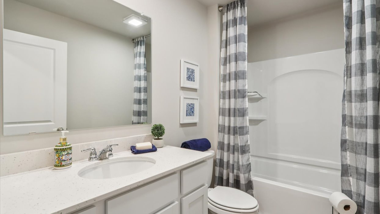 first bathroom with mirror and dual sinks with shower