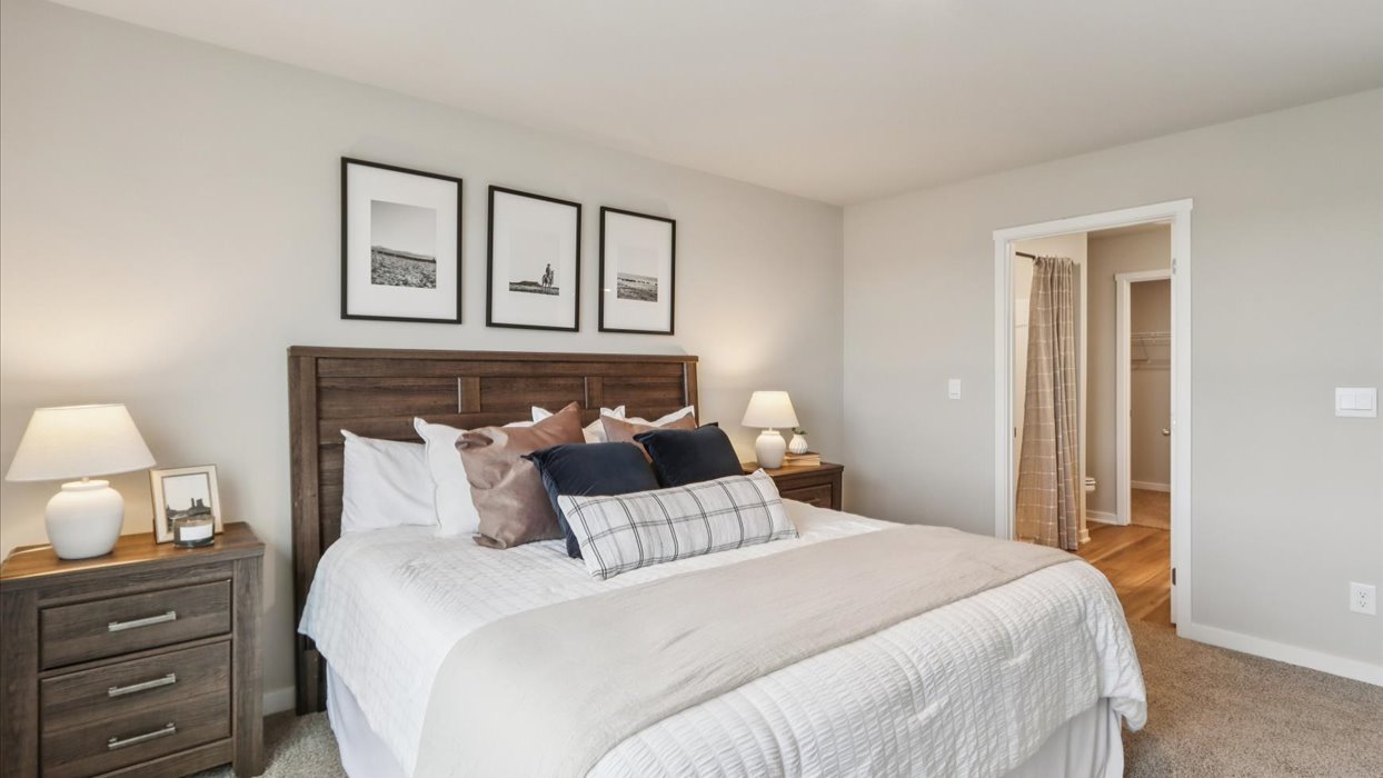 primary bedroom with white bed and view of bathroom