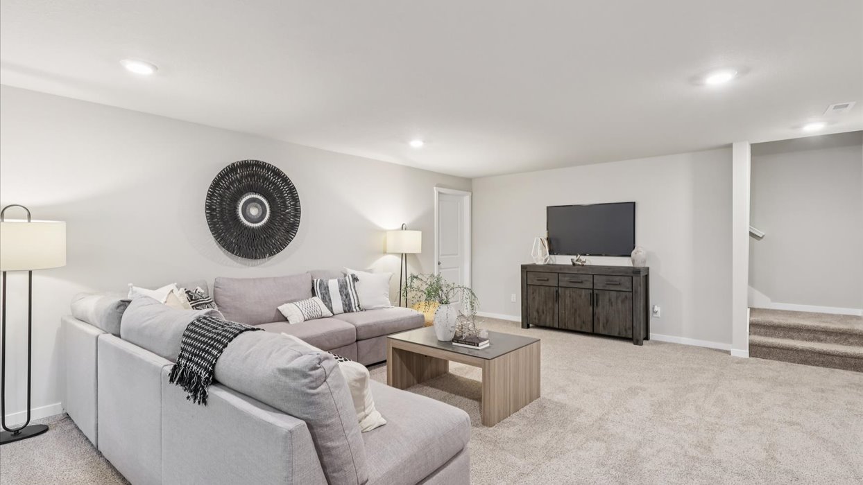 finished basement with overhead lighting and grey couch