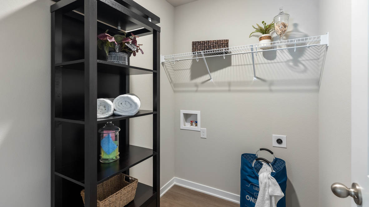 Dedicated laundry room with built-in shelving and utility connections.