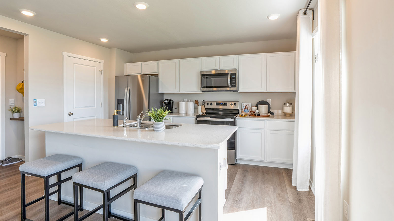 Kitchen with stainless steel appliances, quartz countertops, and white cabinetry