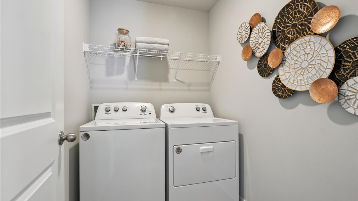 Dedicated laundry room with built-in shelving and utility connections.