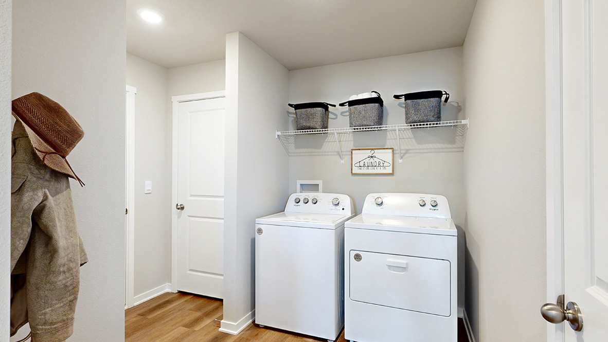 Dedicated laundry room with built-in shelving and utility connections.