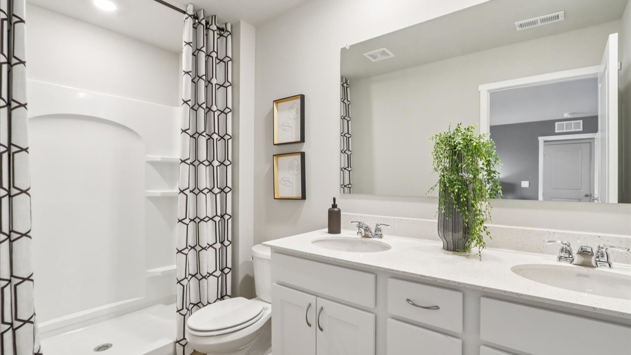 Spacious primary bathroom featuring dual vanities, modern fixtures, and a walk-in shower.