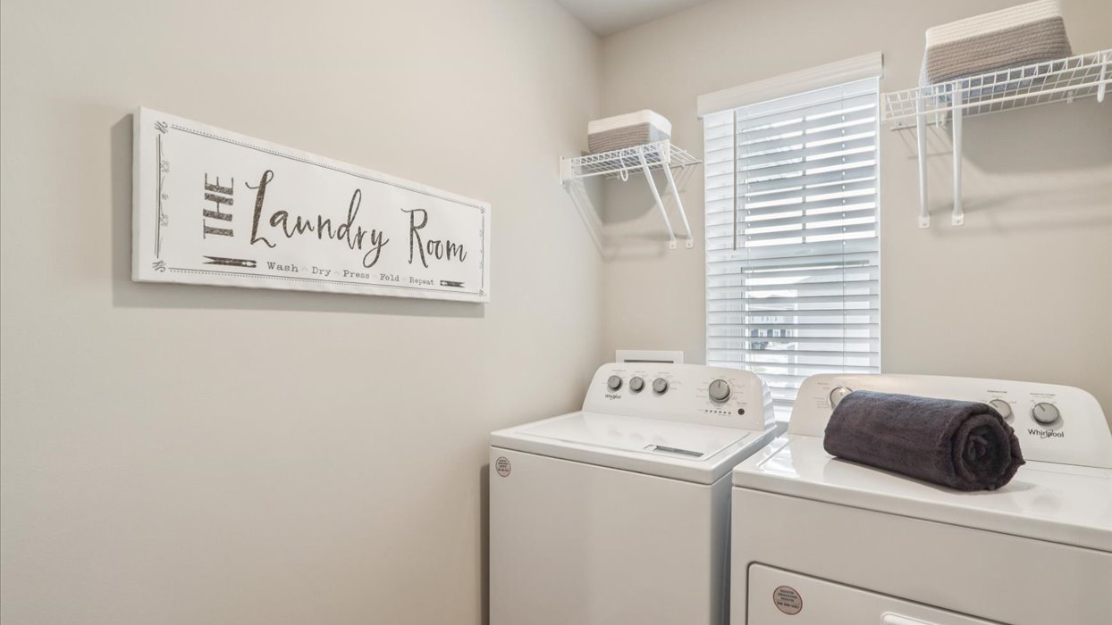 Dedicated laundry room with built-in shelving and utility connections.
