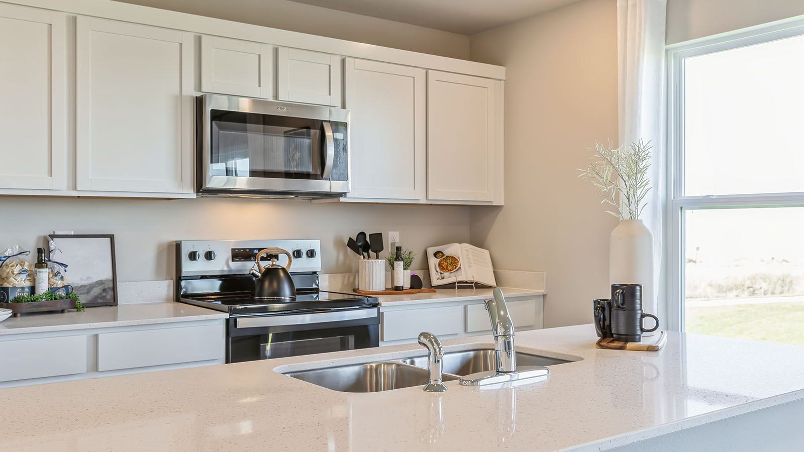Kitchen with stainless steel appliances, quartz countertops, and white cabinetry