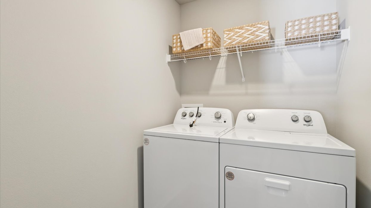 Dedicated laundry room with built-in shelving and utility connections.