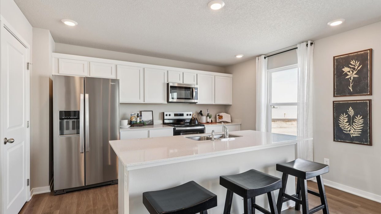 Kitchen with stainless steel appliances, quartz countertops, and white cabinetry