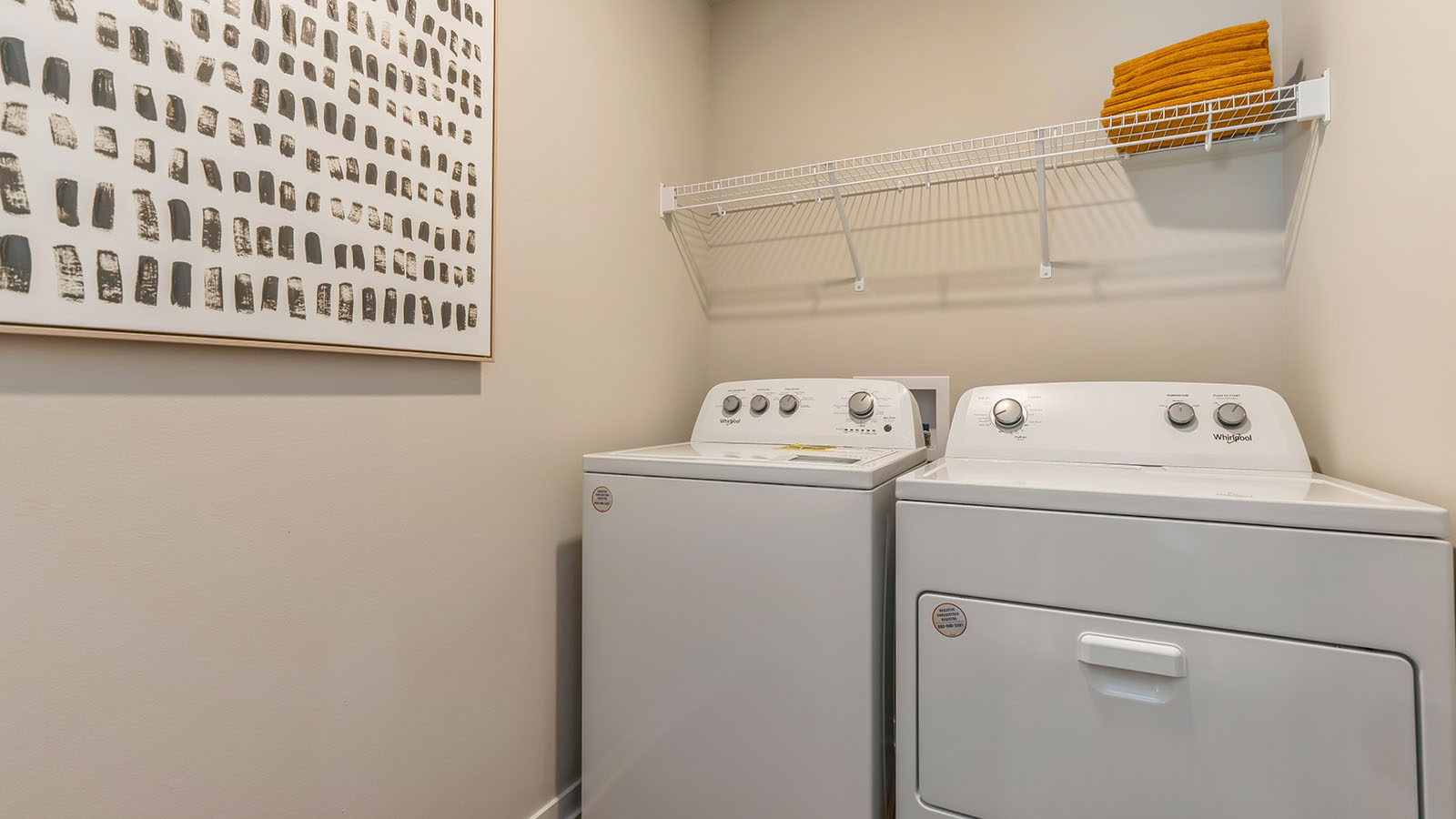 Dedicated laundry room with built-in shelving and utility connections.