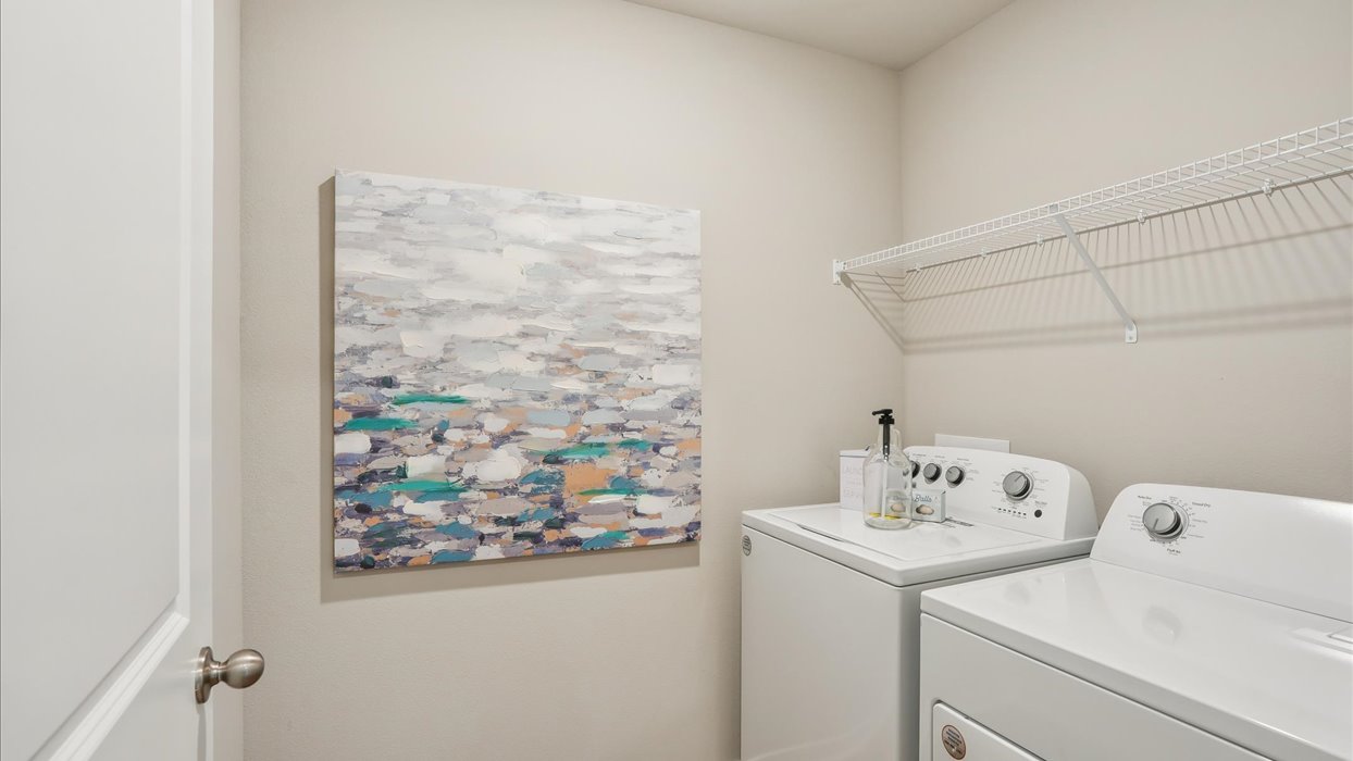 Dedicated laundry room with built-in shelving and utility connections.