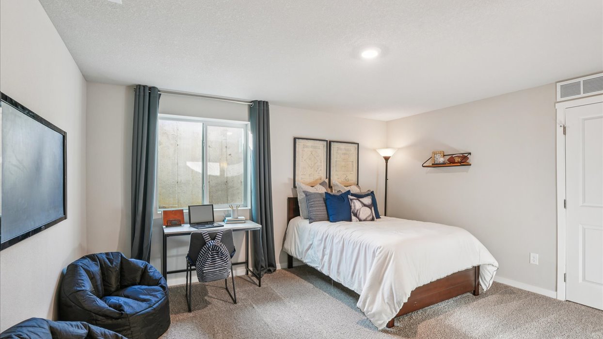 Private lower-level bedroom with natural light and functional storage space.