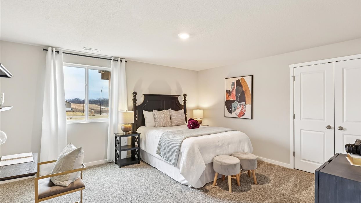 Private lower-level bedroom with natural light and functional storage space.