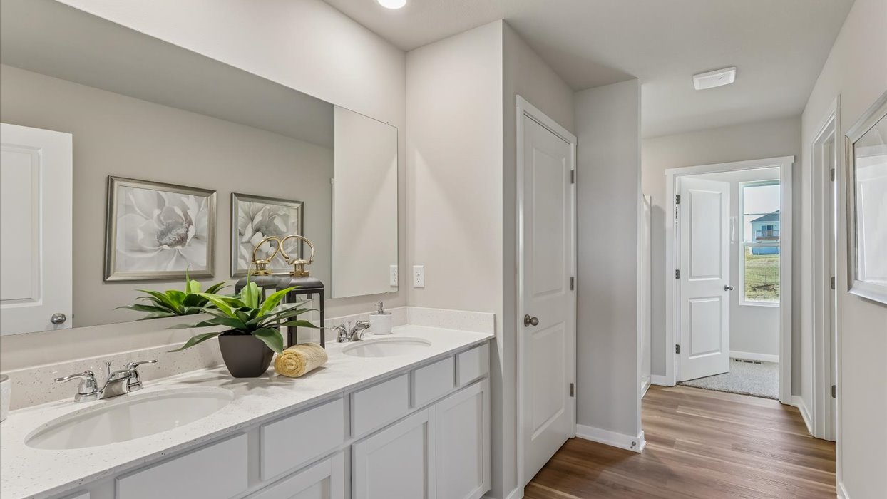 Spacious primary bathroom featuring dual vanities, modern fixtures, and a walk-in shower.