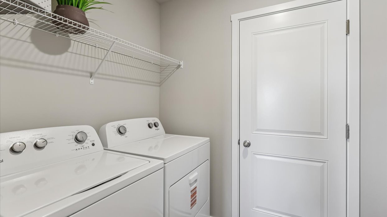 Dedicated laundry room with built-in shelving and utility connections.