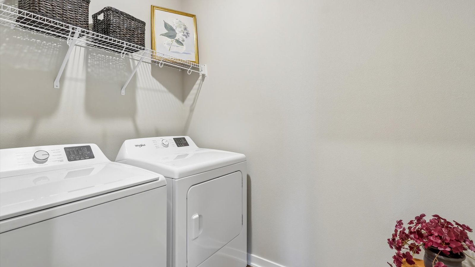 Dedicated laundry room with built-in shelving and utility connections.