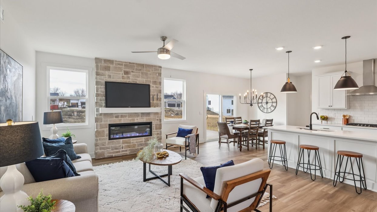 Main level living room offers refined flair with electric fireplace, open concept connections to outdoors, kitchen and living spaces