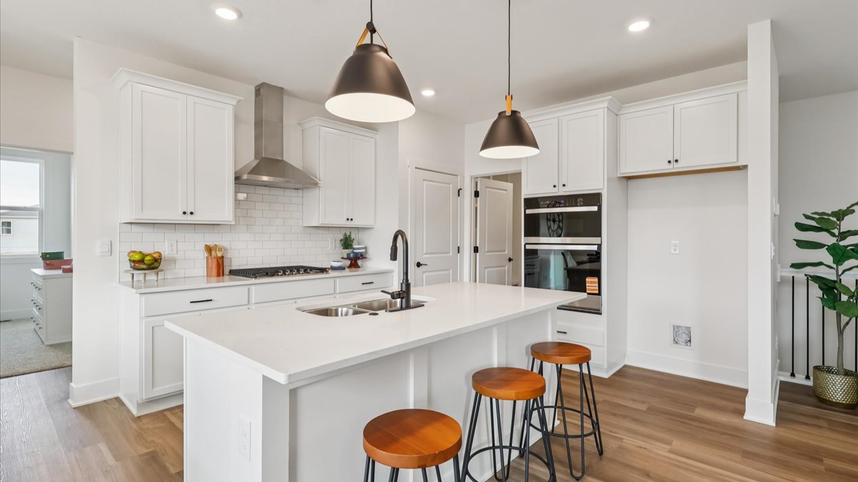 Central kitchen island designed to anchor the home with appliance suite included, sink, pantry, and multi-prep zones