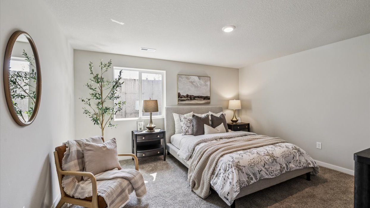 bedroom in basement with white bed and mirror on wall