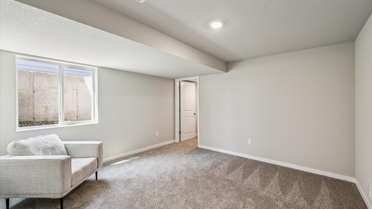 bedroom in finished basement with overhead lighting and window