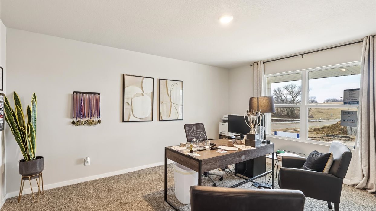 first bedroom staged as an office with desks and chairs