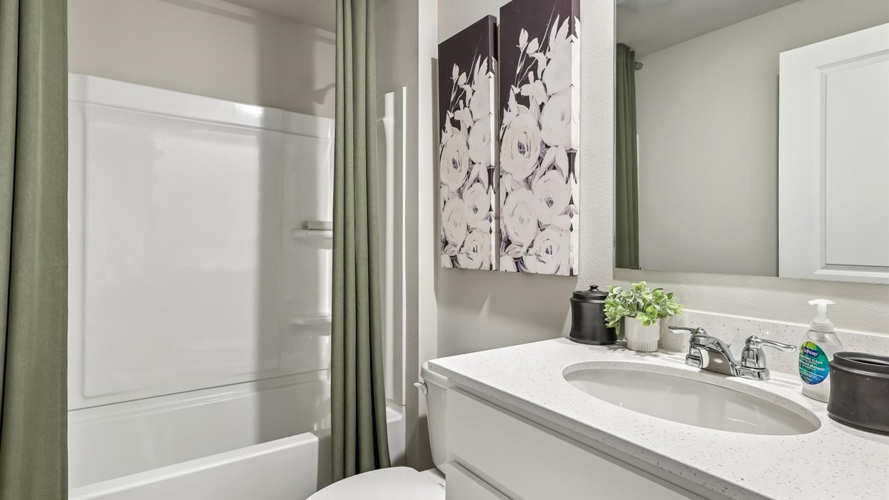 first bathroom with quartz countertops and bathtub