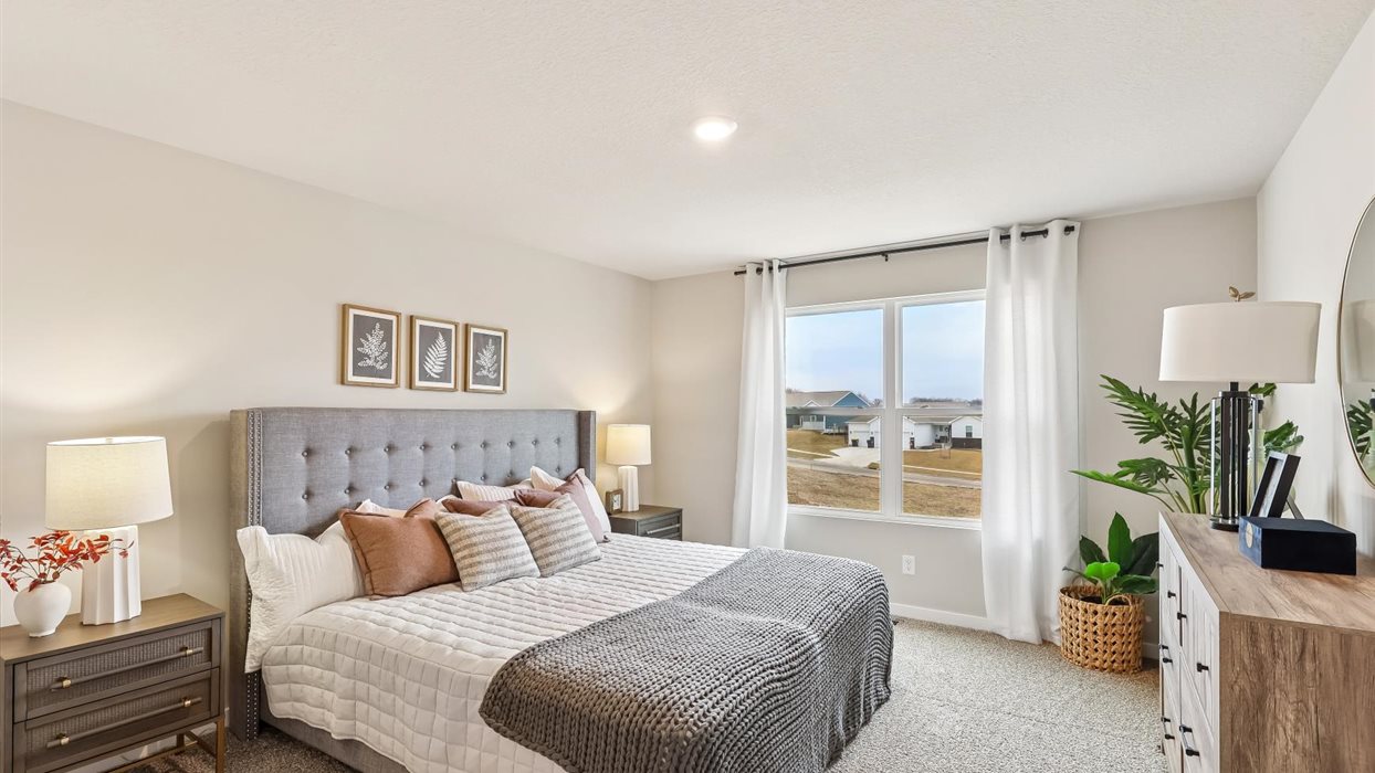 primary bedroom with large window and bed with nightstands