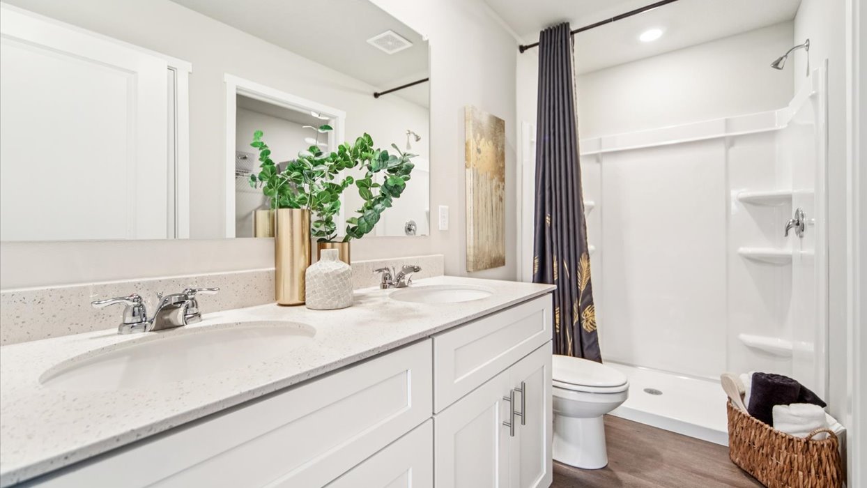 Spacious primary bathroom featuring dual vanities, modern fixtures, and a walk-in shower.
