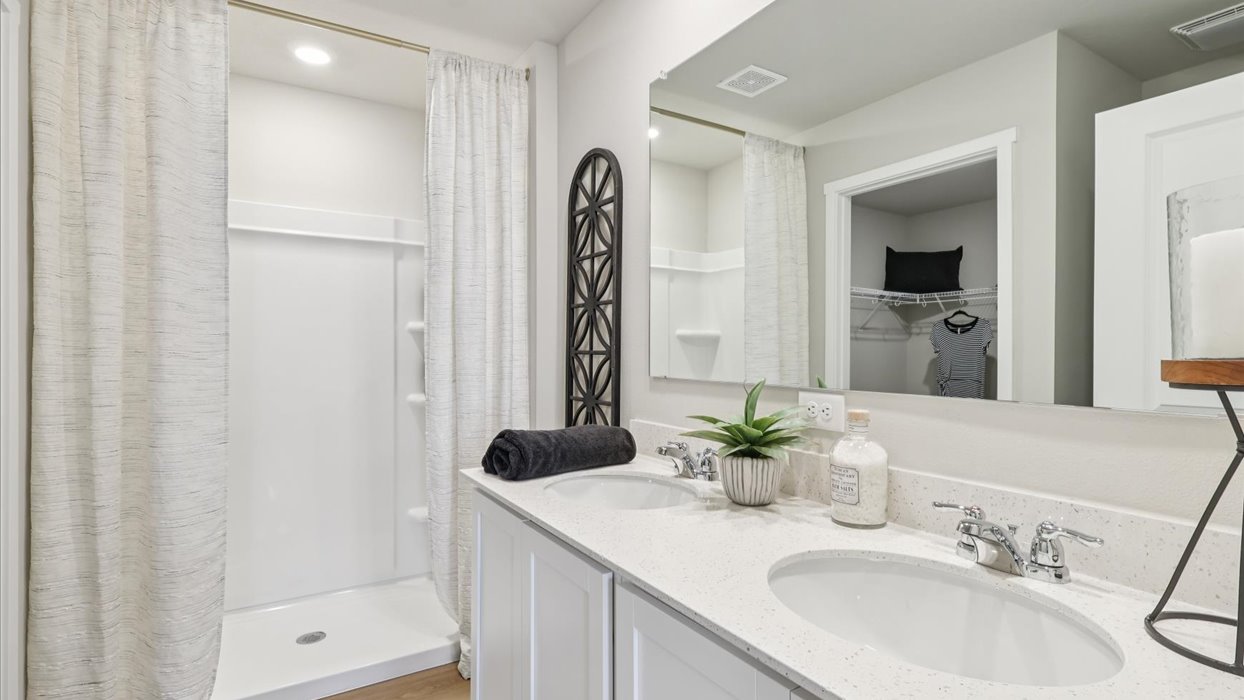 Spacious primary bathroom featuring dual vanities, modern fixtures, and a walk-in shower.