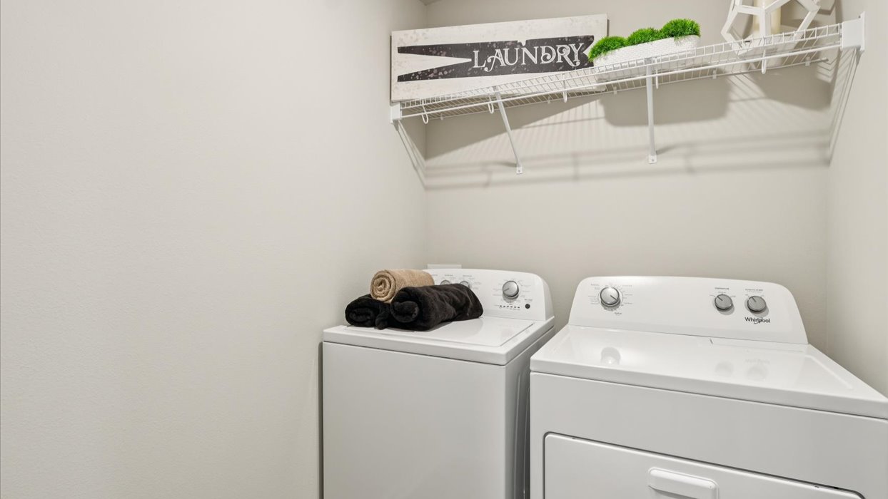 Dedicated laundry room with built-in shelving and utility connections.