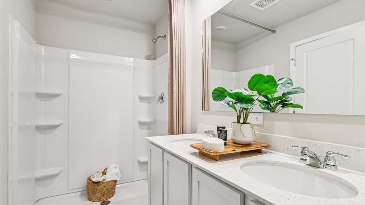primary bathroom with large mirror and dual sinks with shower