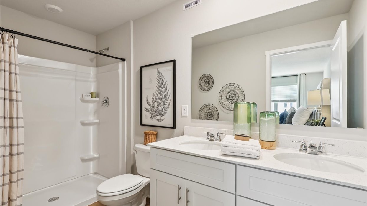 Spacious primary bathroom featuring dual vanities, modern fixtures, and a walk-in shower.