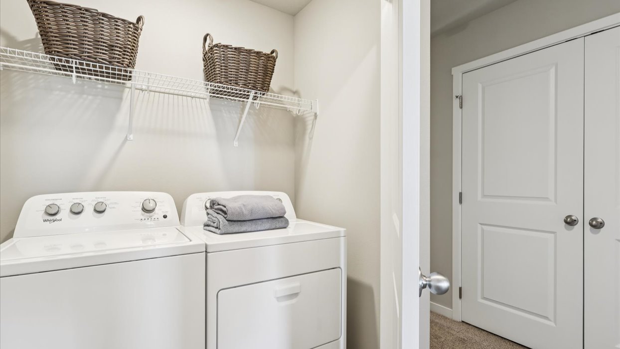 Cozy laundry space with natural light, a washer and dryer, and shelving for supplies.