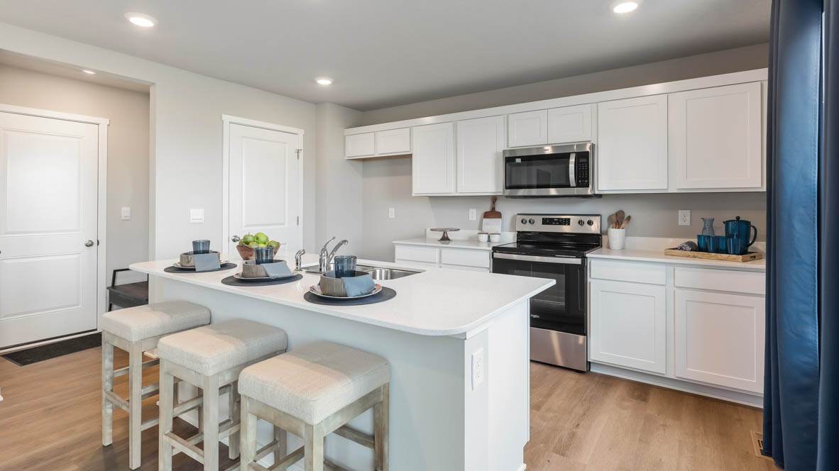 Kitchen with stainless steel appliances, quartz countertops, and white cabinetry