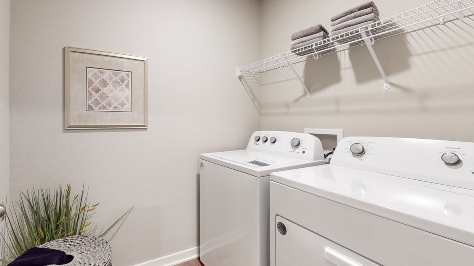 Dedicated laundry room with built-in shelving and utility connections.