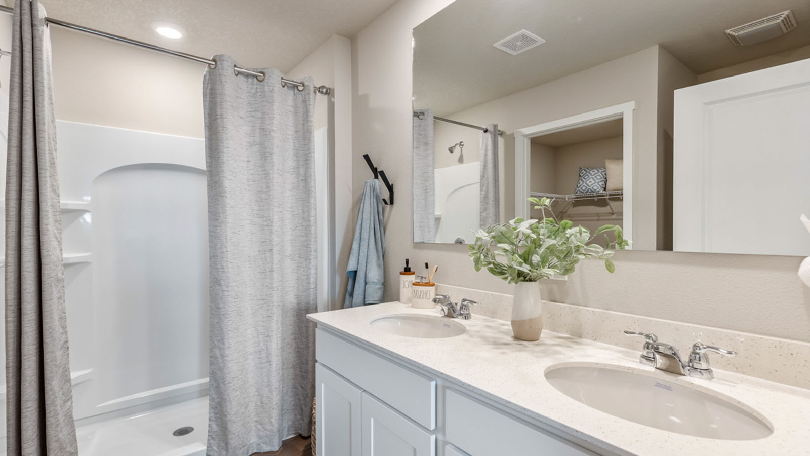 Spacious primary bathroom featuring dual vanities, modern fixtures, and a walk-in shower.