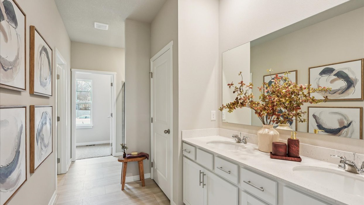 Spacious primary bathroom featuring dual vanities, modern fixtures, and a walk-in shower.