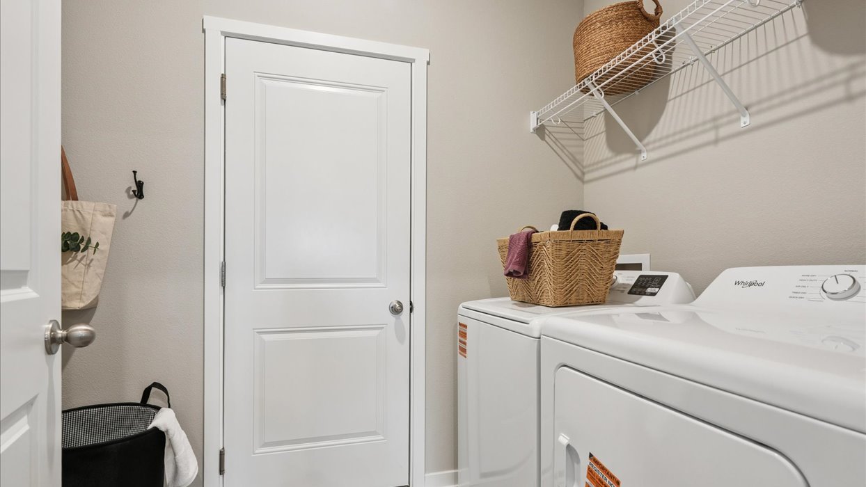 Dedicated laundry room with built-in shelving and utility connections.