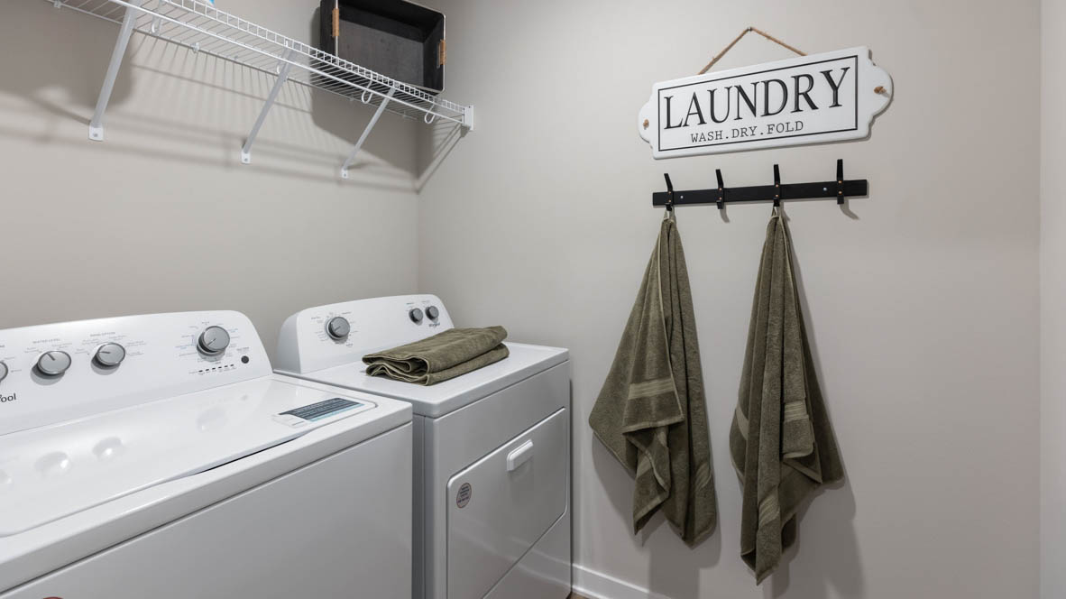 Dedicated laundry room with built-in shelving and utility connections.