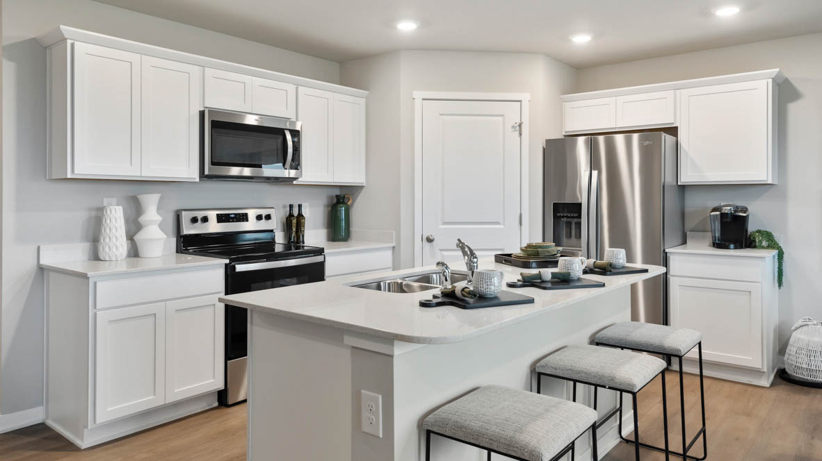 Kitchen with stainless steel appliances, quartz countertops, and white cabinetry