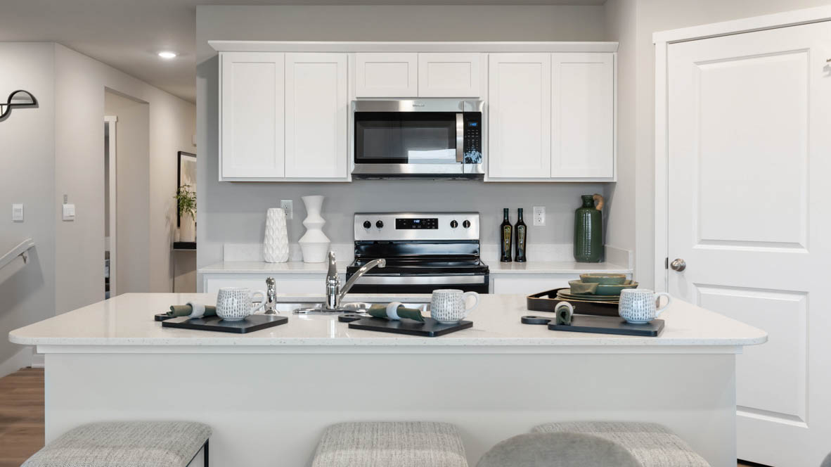 Kitchen with stainless steel appliances, quartz countertops, and white cabinetry
