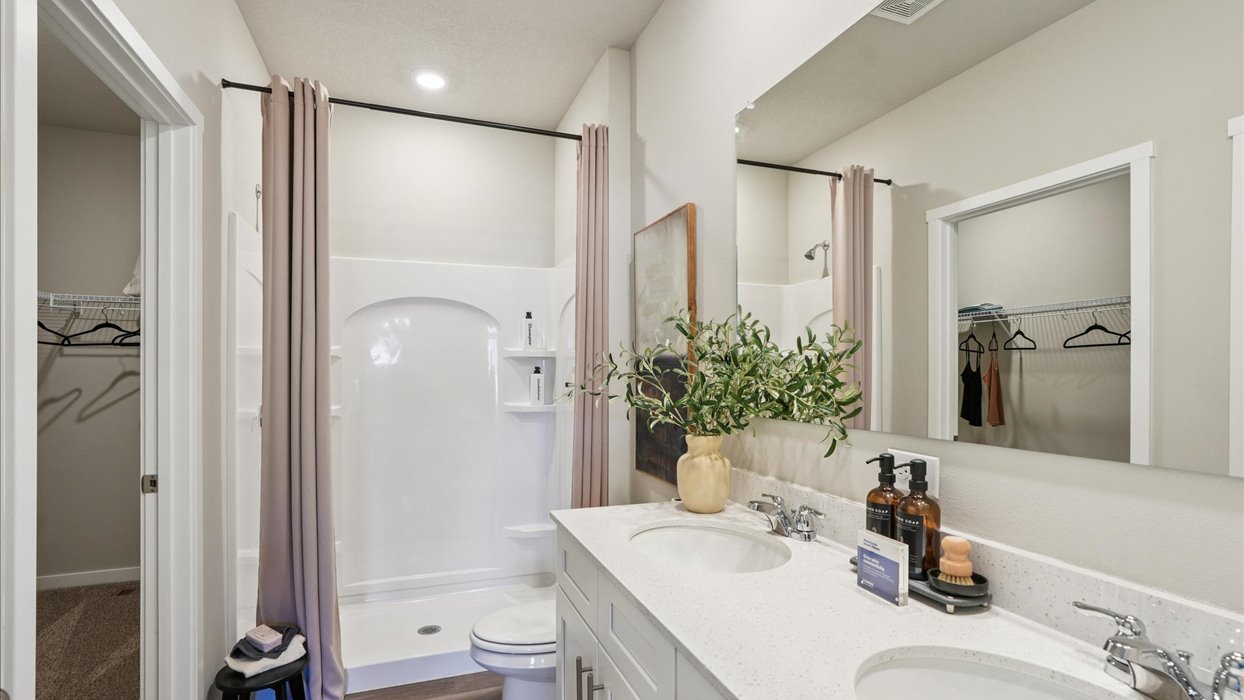 Spacious primary bathroom featuring dual vanities, modern fixtures, and a walk-in shower.